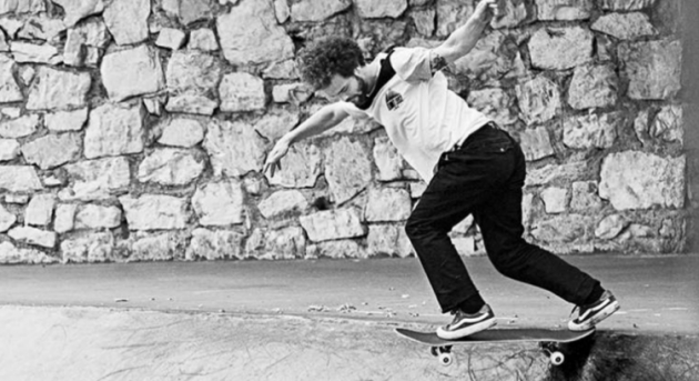 Mann auf Skateboard vor einer Mauer in schwarz-weiß