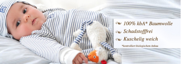 Baby in heller Kleidung auf einer Decke mit Spielzeug