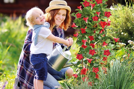 Mutter und Kind mit Gießkanne in einem Garten 