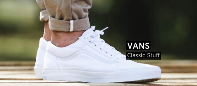 Vans Classic Stuff, Füße mit weißem Paar Vans auf Holzuntergund